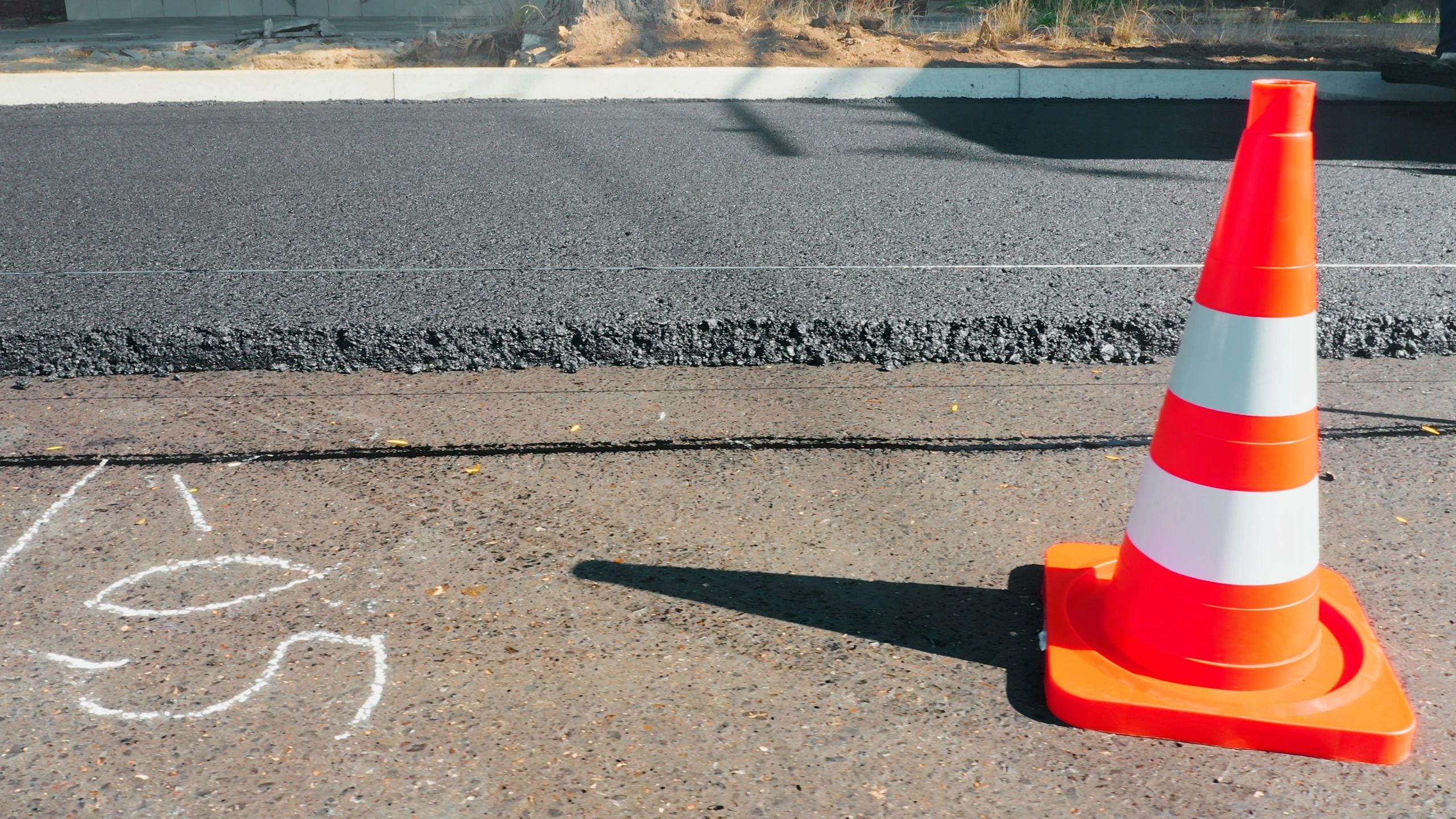 Traffic cone on fresh asphalt representing a facility repair project