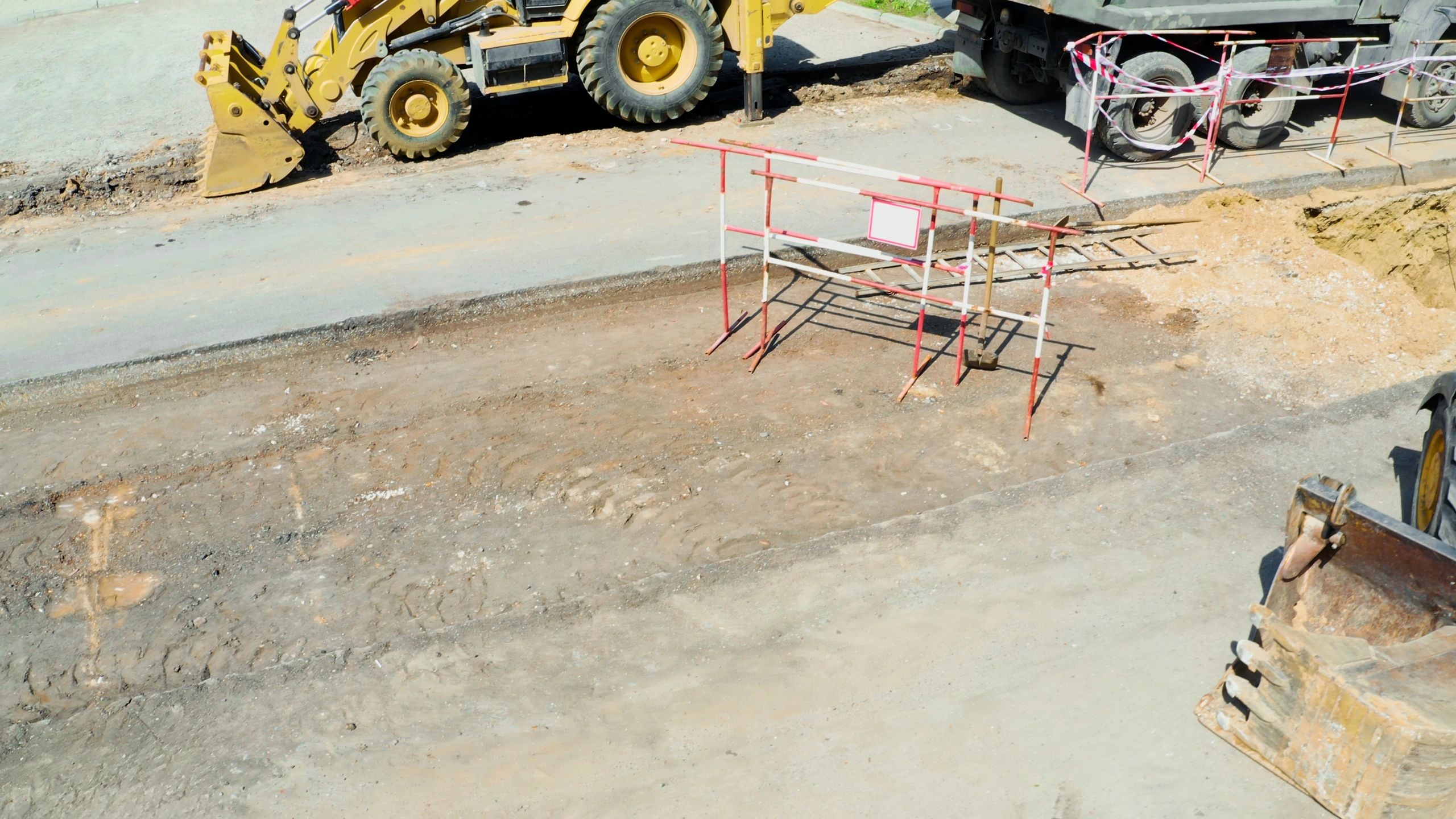 Excavation equipment preparing stone base and grading for asphalt paving project.