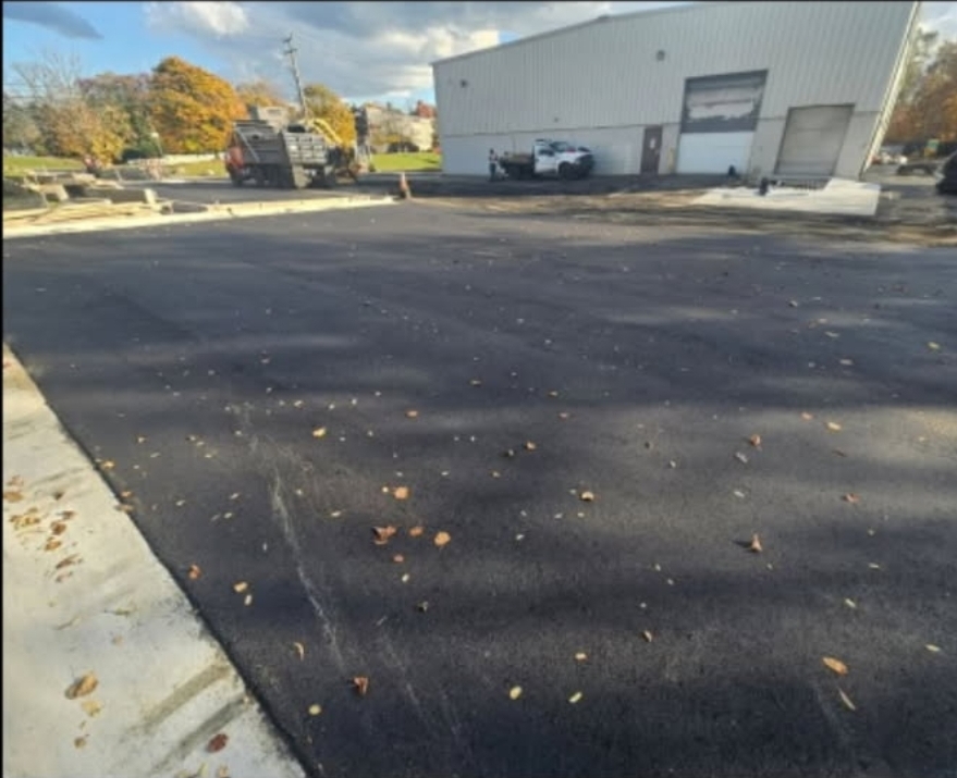 New commercial parking lot asphalt installation with grading and base preparation.