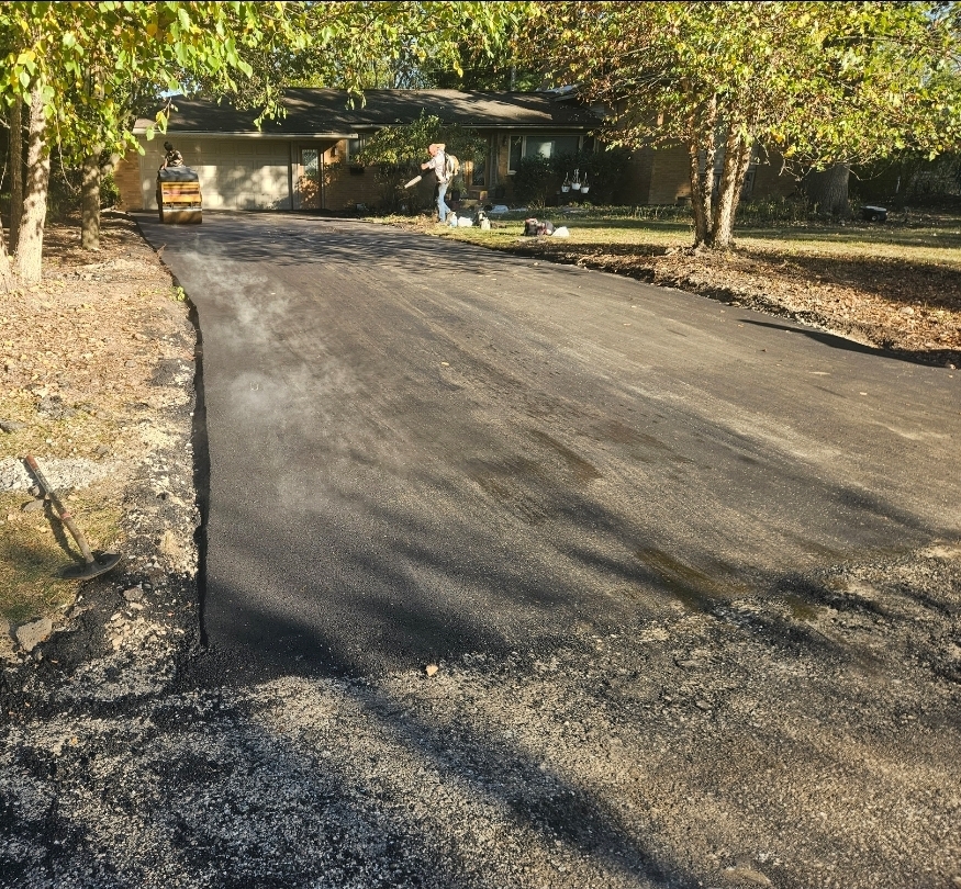 Residential asphalt driveway paving project near garage entrance.