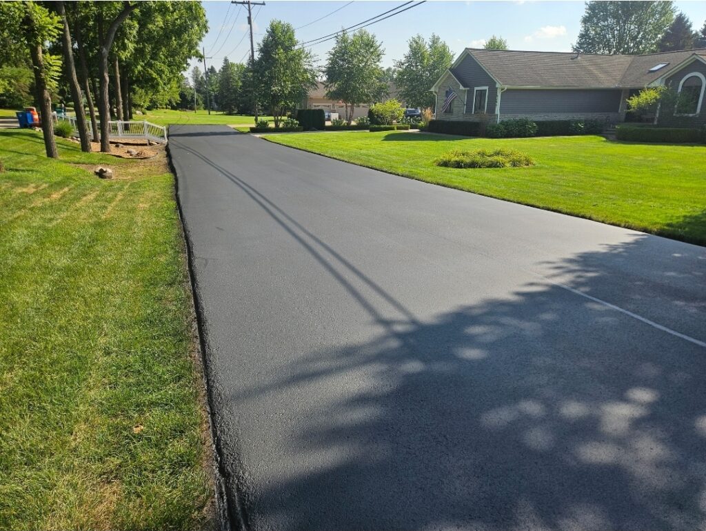 Newly paved residential asphalt driveway with smooth blacktop finish.