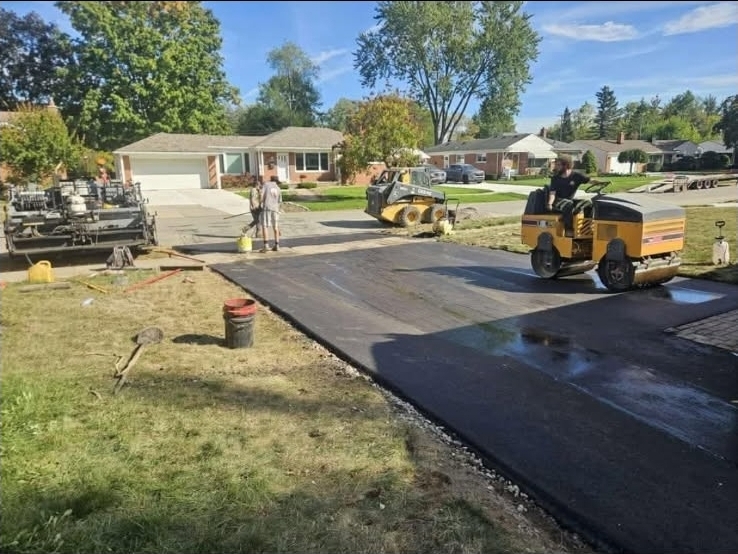 Residential asphalt driveway paving with roller compaction.