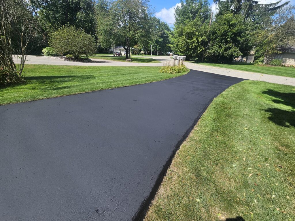 Residential asphalt driveway sealcoating with smooth black finish.