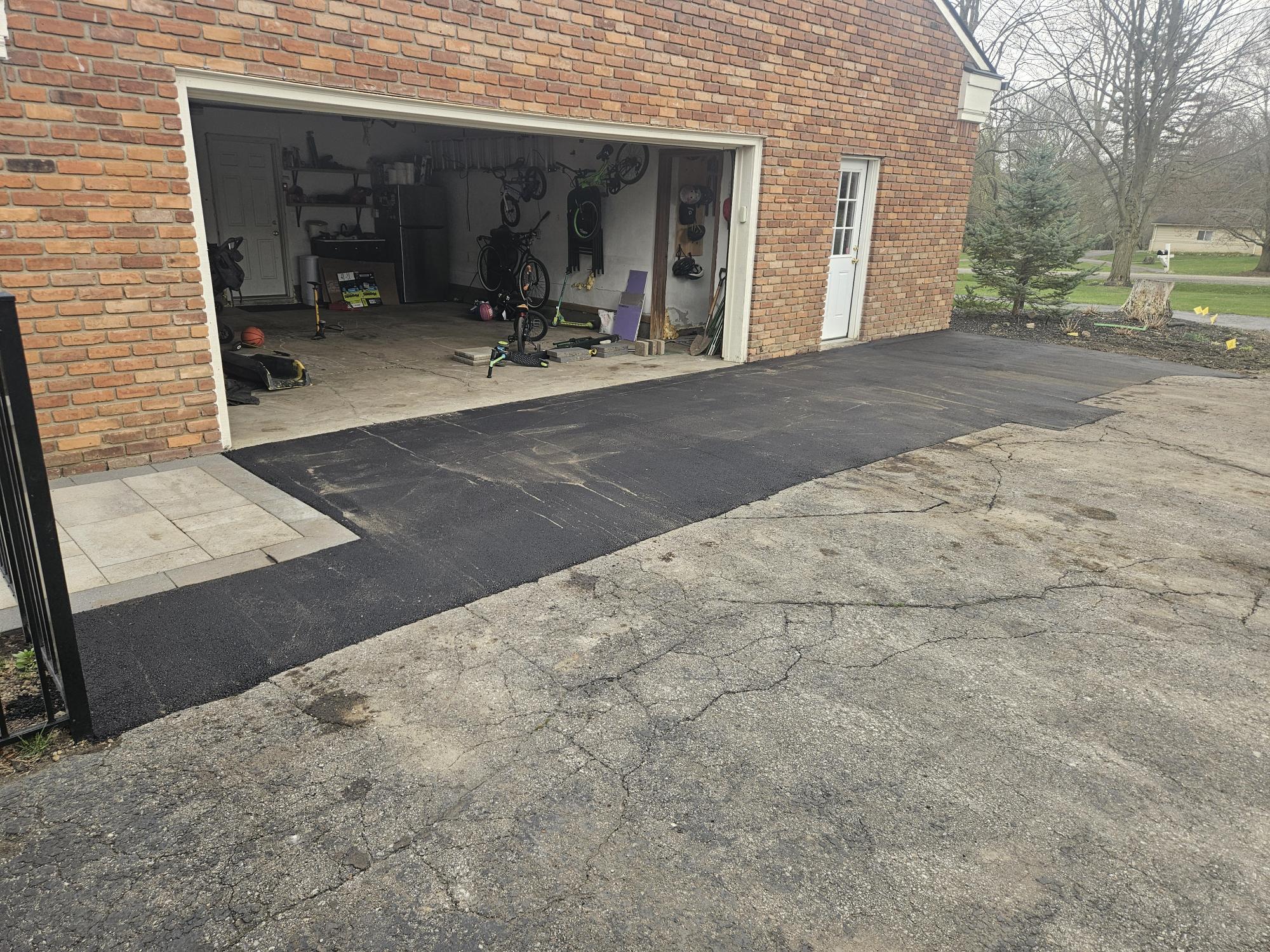 Residential asphalt driveway replacement at garage entrance.
