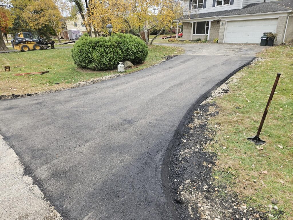 Fresh asphalt driveway replacement with curved residential layout.