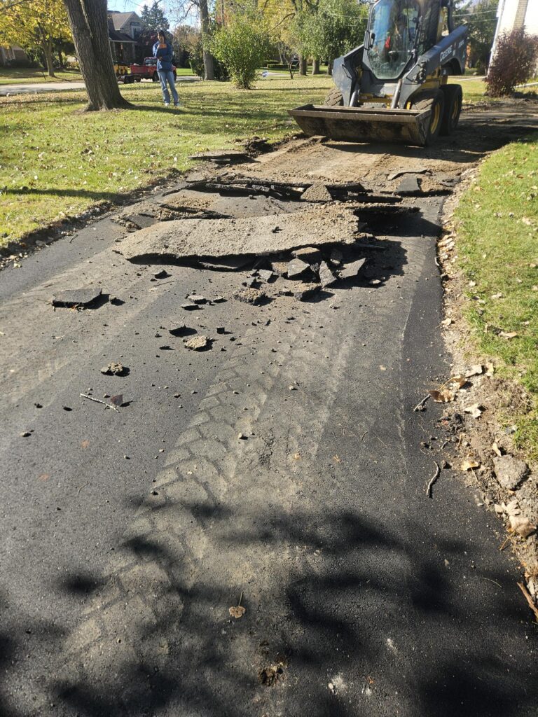 Skid steer removing broken asphalt for patch repair replacement.